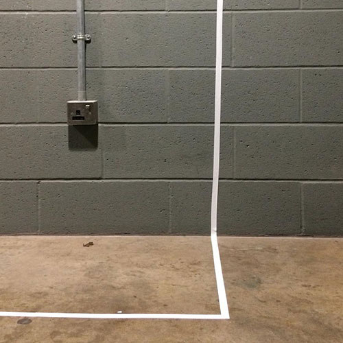 A white taped line from the floor to a wall